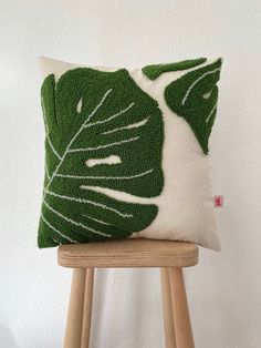 a green and white pillow sitting on top of a wooden stool