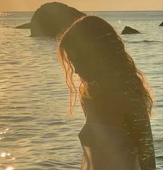 a woman standing in the water with her hair blowing back