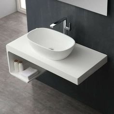 a white bathroom sink sitting on top of a counter next to a wall mounted mirror