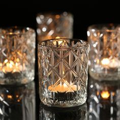 three clear glass candles sitting on top of a black table next to eachother