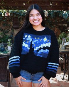 a woman standing in front of a table wearing a sweater with an image of a cat on it