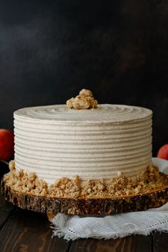 a close up of a cake on a table with apples in the back ground and an apple behind it