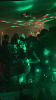 a group of people standing around in a room with green and red lights on the ceiling