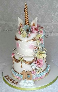 a three tiered cake decorated with flowers and an unicorn's horn