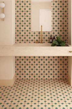 the bathroom is decorated with green and white tiles on the walls, along with a gold faucet