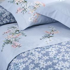 a bed with blue sheets and white flowers on it