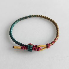 two bracelets with beads on them sitting on top of a white surface, one is gold and the other is green