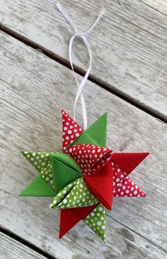 an origami christmas tree decoration hanging on a wooden table with polka dot ribbon