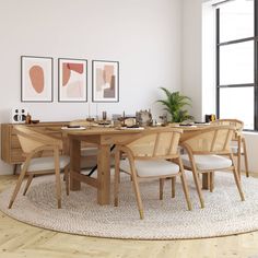 a dining room table with chairs and pictures on the wall above it, along with an area rug