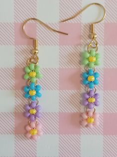 two pairs of colorful beaded earrings on a pink and white checkered tablecloth