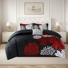 a bed with black and red comforters in a white room next to two lamps