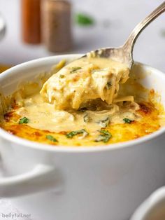 a spoon full of cheese sauce in a white bowl