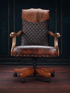 an office chair with leather upholstered back and arm rests on a wooden floor