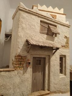 an old building with a wooden door and window on the front side, in a museum display