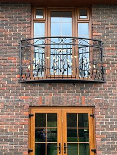 an iron balcony railing on the side of a brick building with double doors and windows