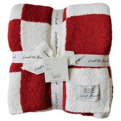 two red and white towels wrapped in paper with tags attached to the ends, tied together