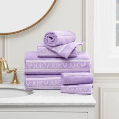 a stack of purple towels sitting on top of a bathroom counter