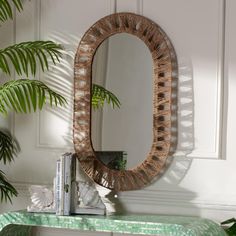 a mirror sitting on top of a wooden table next to a green leafy plant