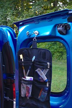 the back end of a blue truck with its door open and various items in it