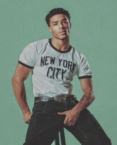 a man sitting on top of a stool wearing a new york city shirt