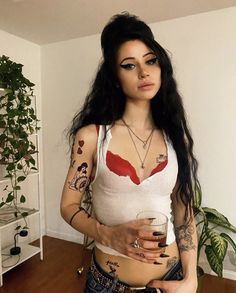 a woman with tattoos holding a drink in her hand