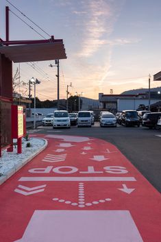 a red and white street sign on the side of a road next to parked cars