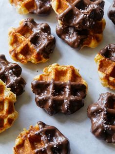 chocolate covered waffles are arranged on a sheet of wax paper and ready to be eaten