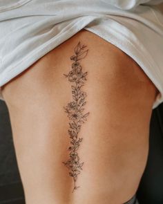 a woman's lower back tattoo with flowers on her left side ribcage