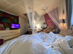 a teddy bear sitting on top of a bed in a room with white sheets and drapes