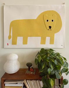 a yellow dog painted on a white wall next to a potted plant and bookshelf