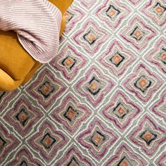 a yellow chair sitting on top of a colorful rug