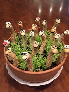 a potted plant filled with lots of fake bugs and grass on top of a wooden table