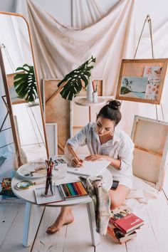 a woman is sitting on the floor with her art supplies and writing in a notebook