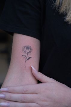 a woman's arm with a small flower tattoo on the left side of her hand