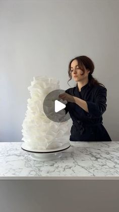 a woman is decorating a white cake with ruffles