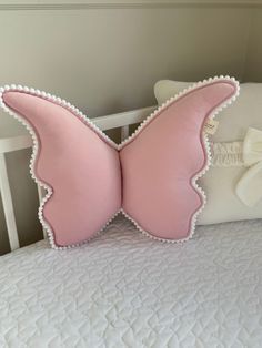 a pink butterfly pillow sitting on top of a white bed