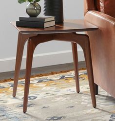 a table with a plant on it next to a brown leather chair and rug in a living room