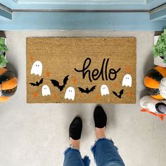 a person standing in front of a door mat that says hello