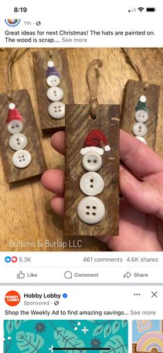 the hand is holding three wooden tags with snowmen on them and one has a santa hat