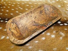 a wooden tray sitting on top of a brown and white spotted animal print blanket with spots