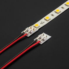 two white leds with red wires on a black surface