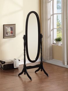 an oval mirror is standing on a stand in the middle of a room with hardwood floors