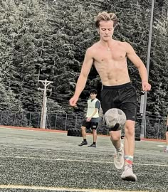 a shirtless young man kicking a soccer ball