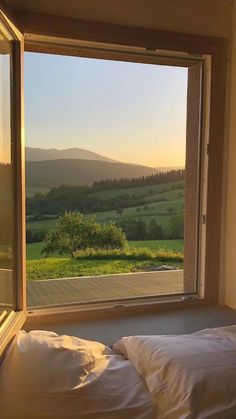 a bed sitting under a window next to a lush green field