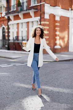 a woman is walking down the street with her arms outstretched and holding a drink in one hand