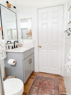 a bathroom with a toilet, sink and mirror in it's corner next to a door