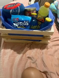 a wooden crate filled with food on top of a bed