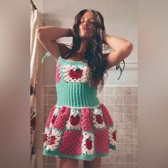 a woman standing in front of a shower wearing a crocheted dress with hearts on it