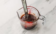 a blender filled with brown liquid sitting on top of a white marble countertop