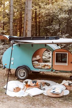 a camper trailer parked in the woods with its door open and food on it